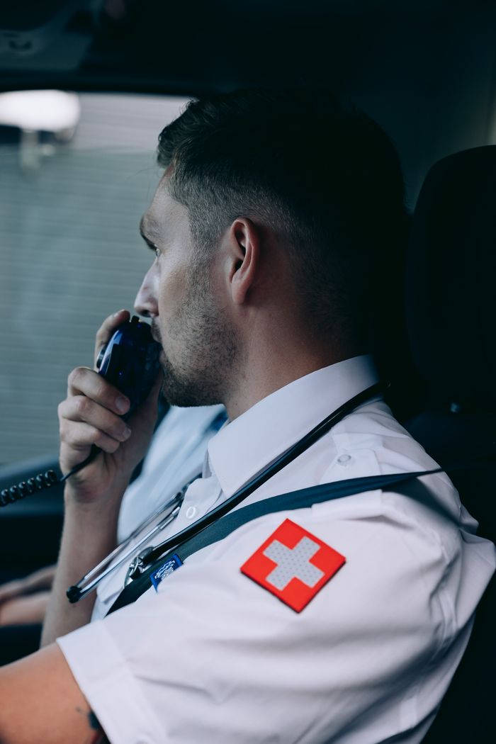 Focused paramedic using radio while seated in ambulance, ready for emergency.